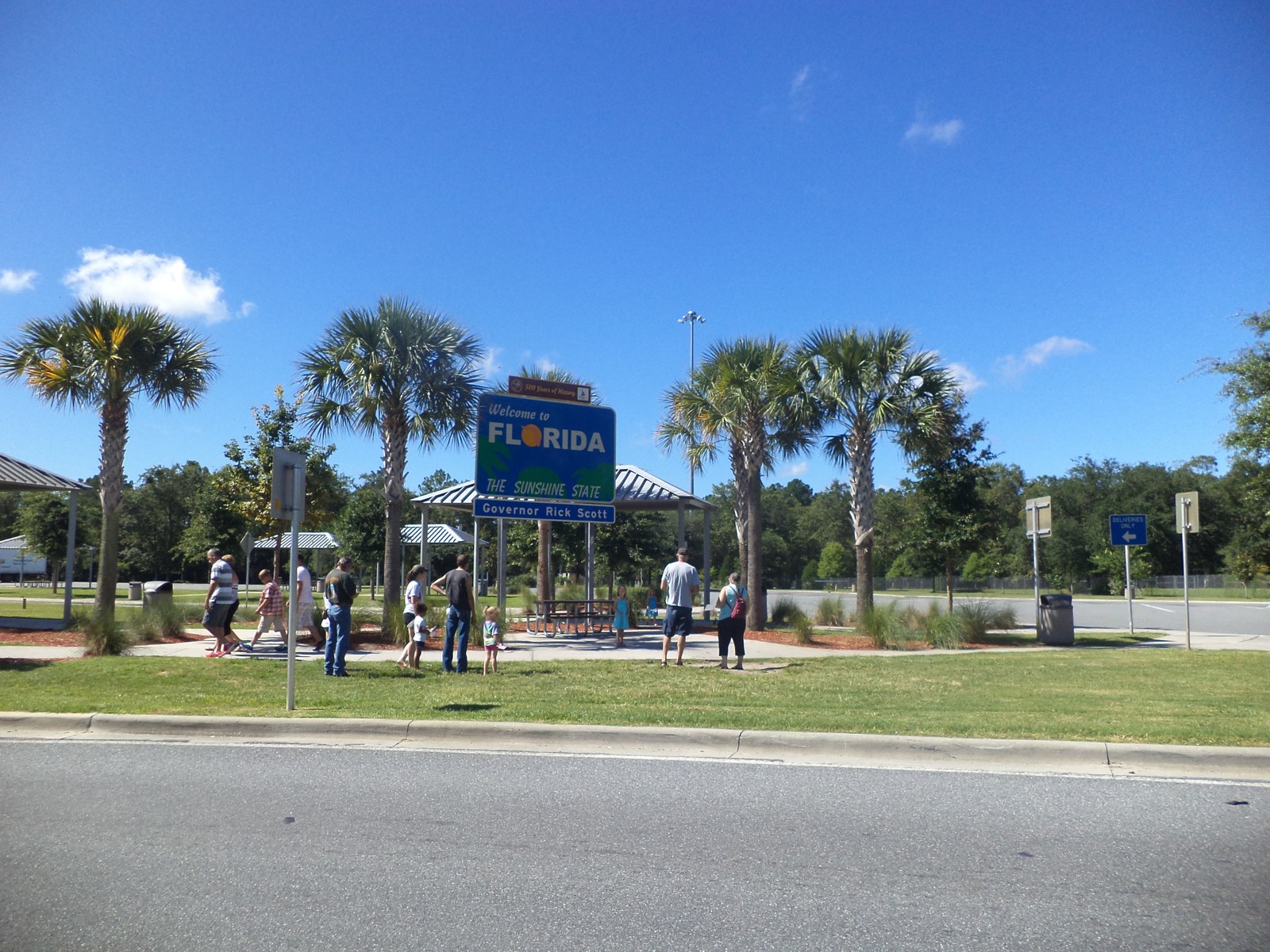 A 'Welcome to Florida' sign at a Florida state welcome center, with visitors nearby, representing a family relocating across state lines.